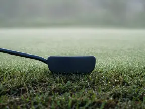 짙은 빛 퍼터가 놓인 그린 가장자리 (연출 이미지)